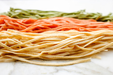 Variety of fresh pasta on marble stone, close up view