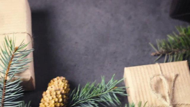 Black and brown paper christmas gift box with pine branches on dark texture surface.