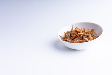 Fried anchovies on white background with selective focus and crop fragment