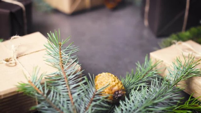 Black and brown paper christmas gift box with pine branches on dark texture surface.