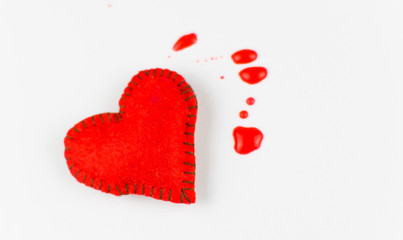 The concept of a bleeding heart. Stitched heart and blood spots on a white background.