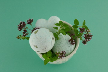 bath bombs with oregano extract.green bath bombs and sprigs of fresh oregano in a green  cup on a...