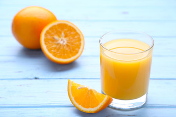 Glass of orange juice with orange on wooden table