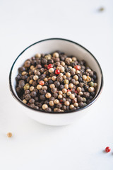 Various kinds of pepper seeds in a white bowl on a white background. Macro photography.