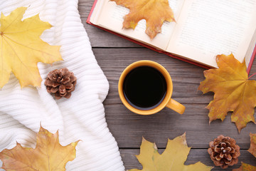 Cup of coffee with autumn leave and old book on wooden background