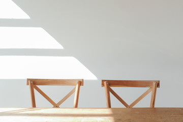 Wooden chair stool and wooden table on white wall background in a cafe with sunlight shade
