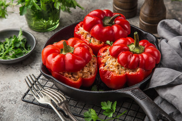 red bell peppers stuffed with meat, rice and vegetables on cast iron pan - obrazy, fototapety, plakaty