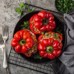 red bell peppers stuffed with meat, rice and vegetables on cast iron pan, top view, square image