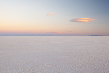 A pastel sunset over the Salar de Uyuni bathes the salt plain in the last soft rays of light and...