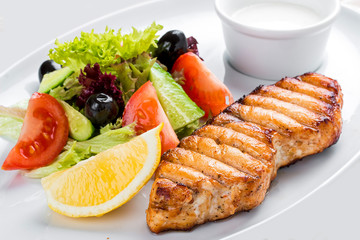 Grilled salmon steak with vegetables. On a white plate