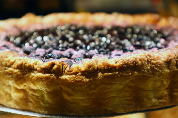 Appetizing black berry pie with crisp in a showcase of pastry shop