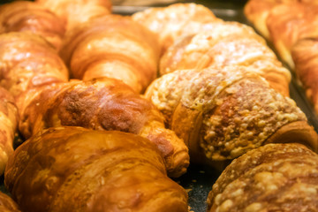 A number of appetizing ruddy croissants on a tray in a showcase