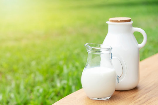 Fresh milk on wood table with green nature background.