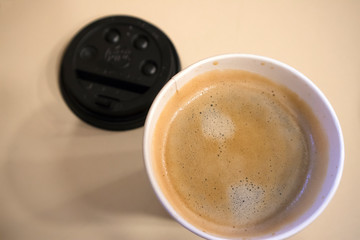 Closeup top view of one-off cup of appetizing morning coffee with foam