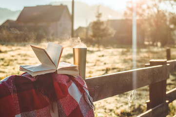 Breakfast with a book in the open air. Steam over a thermo cup. Open book on nature. Book and drinking coffee. Reading at outdoor