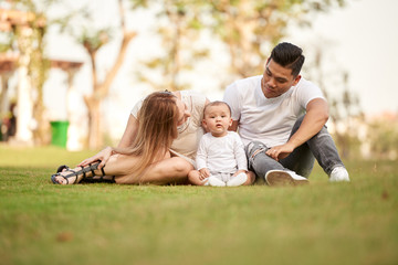 Naklejka na ściany i meble Young family with toddler boy having picnic in city park