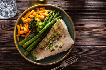 Pike perch fillet with asparagus, broccoli and carrots. Fried fish with stewed greens