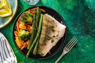Pike perch fillet with asparagus, broccoli and carrots. Fried fish with stewed greens