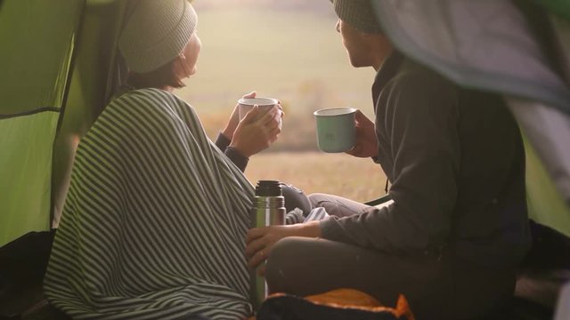 Two people drink hot tea in the tent