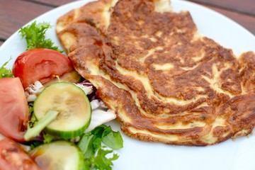 Golden cooked omelette with side salad served on a white plate 