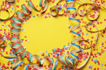 confetti and paper streamer frame on yellow background - party celebration concept flat lay with...