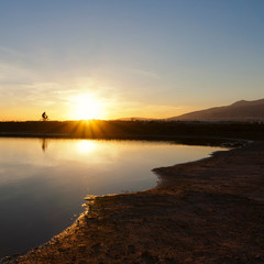Puesta de sol cerca del mar contraluz persona en bicicleta en Almer&iacute;a 