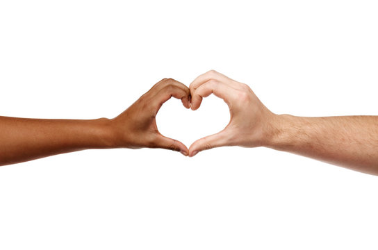 charity, love and diversity concept - close up of female and male hands of different skin color making heart shape