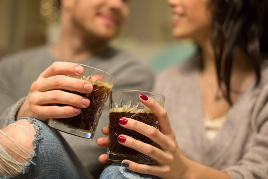 hygge, leisure and people concept - close up of happy couple drinking coffee at home