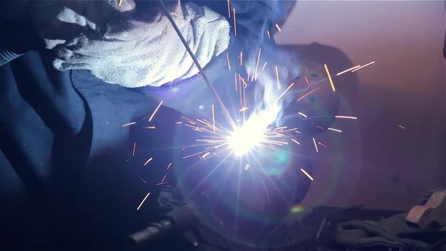 welder welds two pieces of steel pipe using electric welding in production