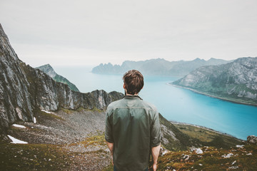 Man adventurer admiring fjord and mountains view Travel lifestyle adventure concept vacations outdoor in Norway solitude calm emotions