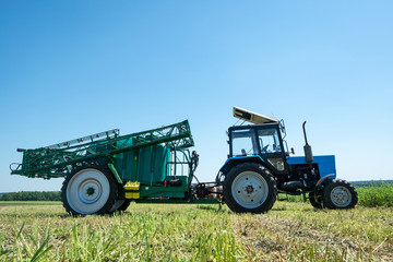 blue tractor in the field is preparing for chemical treatment of plants