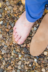 Natural physiotherapy for flat feet. Female foot on the surface of the pebbles and leather orthopedic insoles  as prevention against platypodia