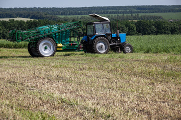 Fototapeta premium blue tractor in the field is preparing for chemical treatment of plants