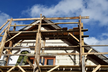 Worker working on wooden scaffolding and installing rigid  polystyrene styrofoam plates on...
