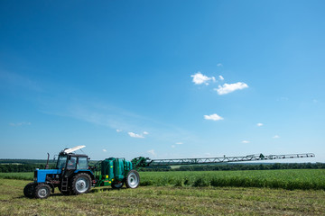 blue tractor in the field is preparing for chemical treatment of plants