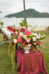 A wedding bouquet in a vase costs around the table, of flowers and greenery - roses, peonies, eustoma, orchids, evalipt, fern