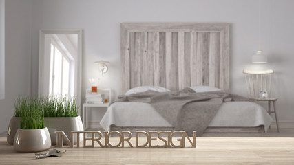 Wooden table, desk or shelf with potted grass plant, house keys and 3D letters making the words interior design, over blurred scandinavian bedroom, project concept copy space background