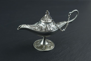 Old style metal oil lamp on black stone background.