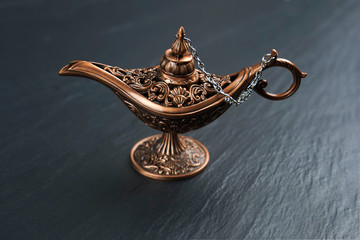  Old style copper oil lamp on black stone background.