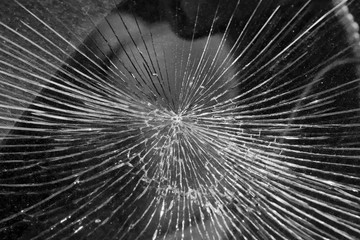 Cracks from the impact on the windshield of the car. The cracks radiate from the center of the impact. Collision with flying stones on the road. Risk and danger of damage. Robbery or vandalism.