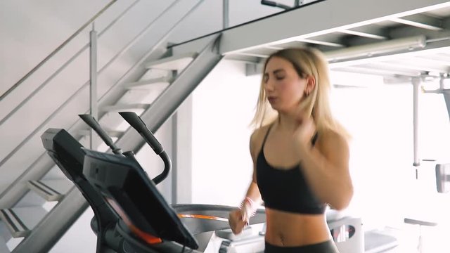 Young woman running on a treadmill in gym fitness club