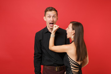 Fun expression young couple in black clothes shirt dress celebrating birthday holiday party isolated on bright red background. St Valentine International Women Day Happy New Year 2019 concept. Mock up