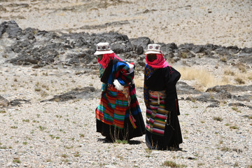 Two women in traditional Tibetan clothes make parikrama around the lake Tere Tashi Namtso in Tibet, China 