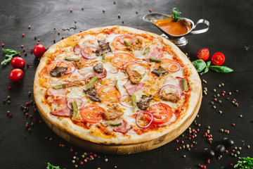 Tasty meat pizza with various ingredients on black background