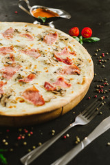 Tasty meat pizza with various ingredients on black background