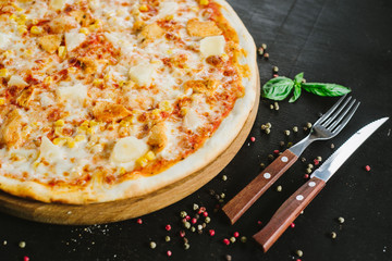 Tasty pizza with ham, corn and cheese on black background