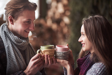 Young couple having breakfast in a romantic cabin outdoors in winter. Winter holiday and vacation. Christmas couple of happy man and woman drink hot wine. Couple in love