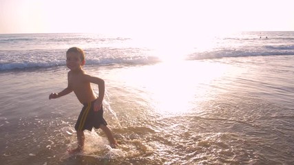 Slow motion - A child 3-5 years old running freely while the camera chase him and he laughs, in a sunny day in the beach 