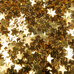 Golden decorate star shaped confetti. Christmas maclground. 
