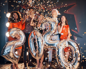 A group of fun young beautiful multinational people throwing confetti at a party. Celebration of...